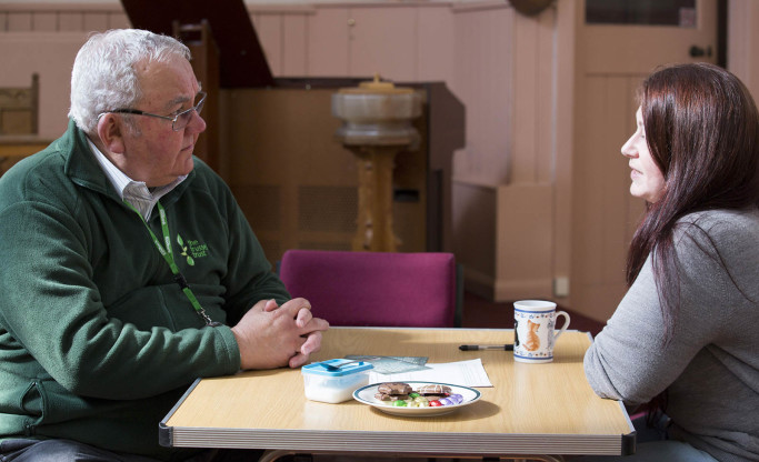 voluteer chatting to client over tea and biscuits